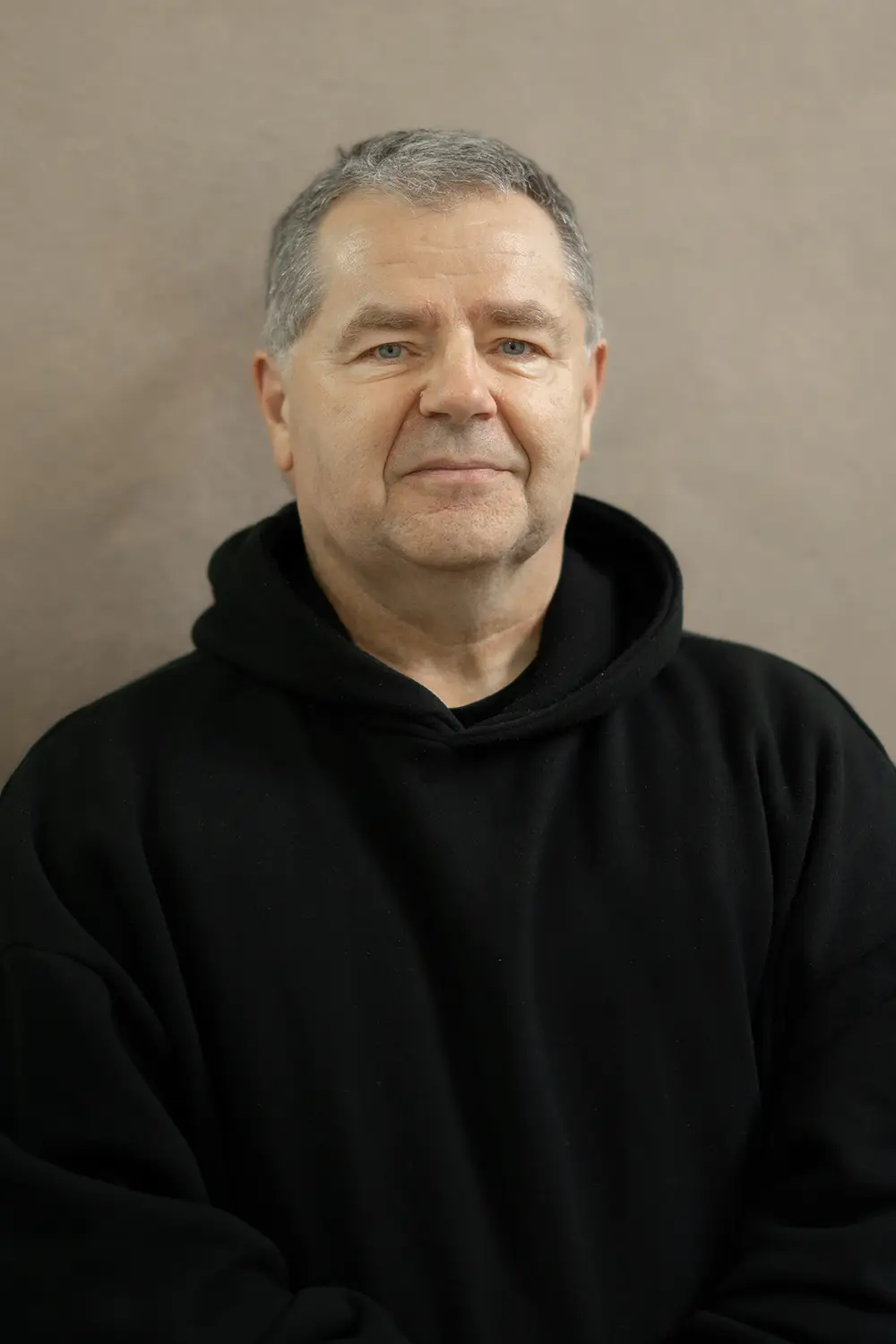 Portrait eines männlichen Trainers im schwarzen Hoodie im Fitnessstudio Body & Soul in Billerbeck, freundlicher Blick in die Kamera.