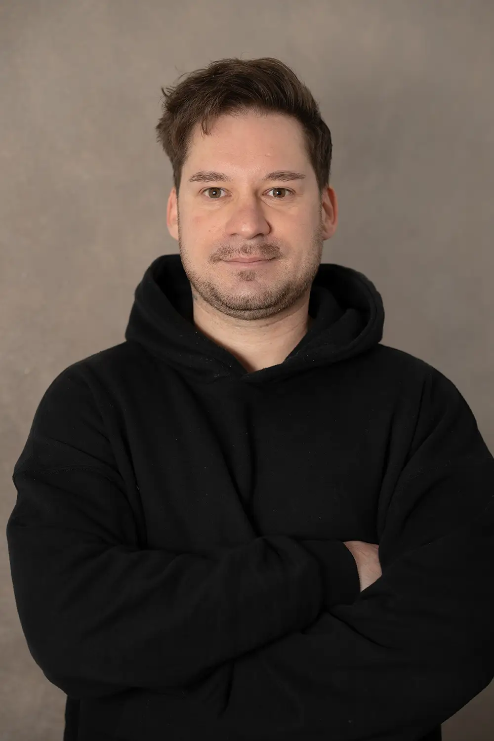 Portrait eines männlichen Trainers im schwarzen Hoodie im Fitnessstudio Body & Soul in Billerbeck, freundlicher Blick in die Kamera.