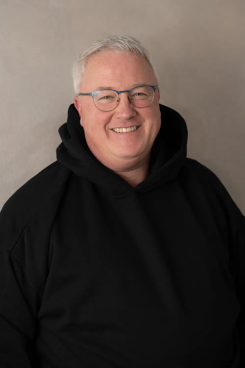 Portrait eines männlichen Trainers im schwarzen Hoodie im Fitnessstudio Body & Soul in Billerbeck, freundlicher Blick in die Kamera.