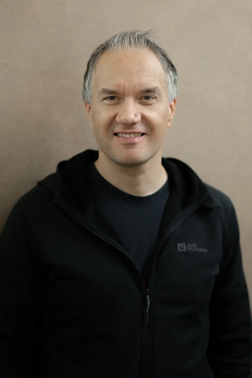 Portrait eines männlichen Trainers im schwarzen Hoodie im Fitnessstudio Body & Soul in Billerbeck, freundlicher Blick in die Kamera.