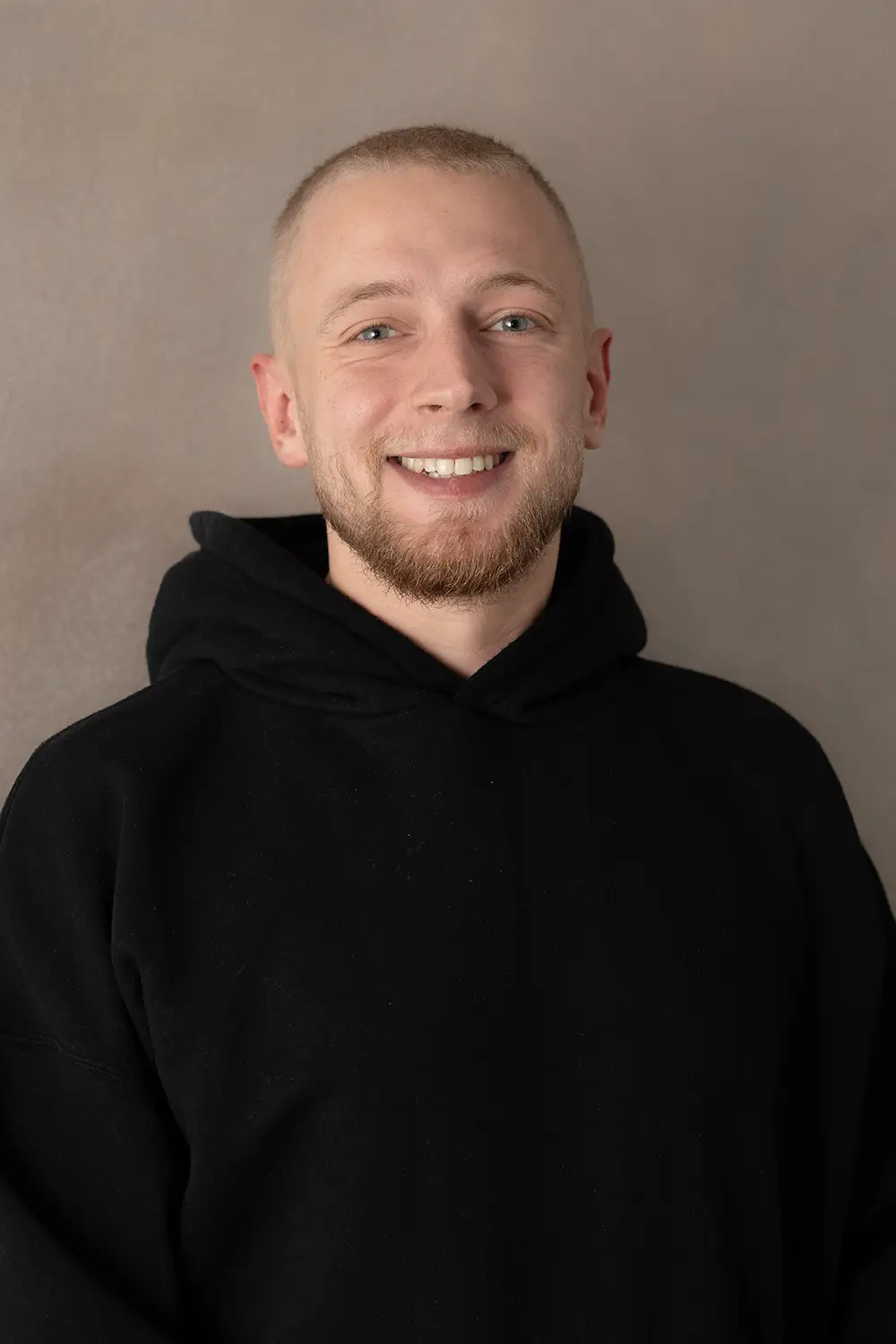 Portrait eines männlichen Trainers im schwarzen Hoodie im Fitnessstudio Body & Soul in Billerbeck, freundlicher Blick in die Kamera.