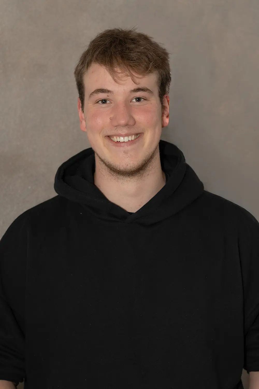 Portrait eines männlichen Trainers im schwarzen Hoodie im Fitnessstudio Body & Soul in Billerbeck, freundlicher Blick in die Kamera.