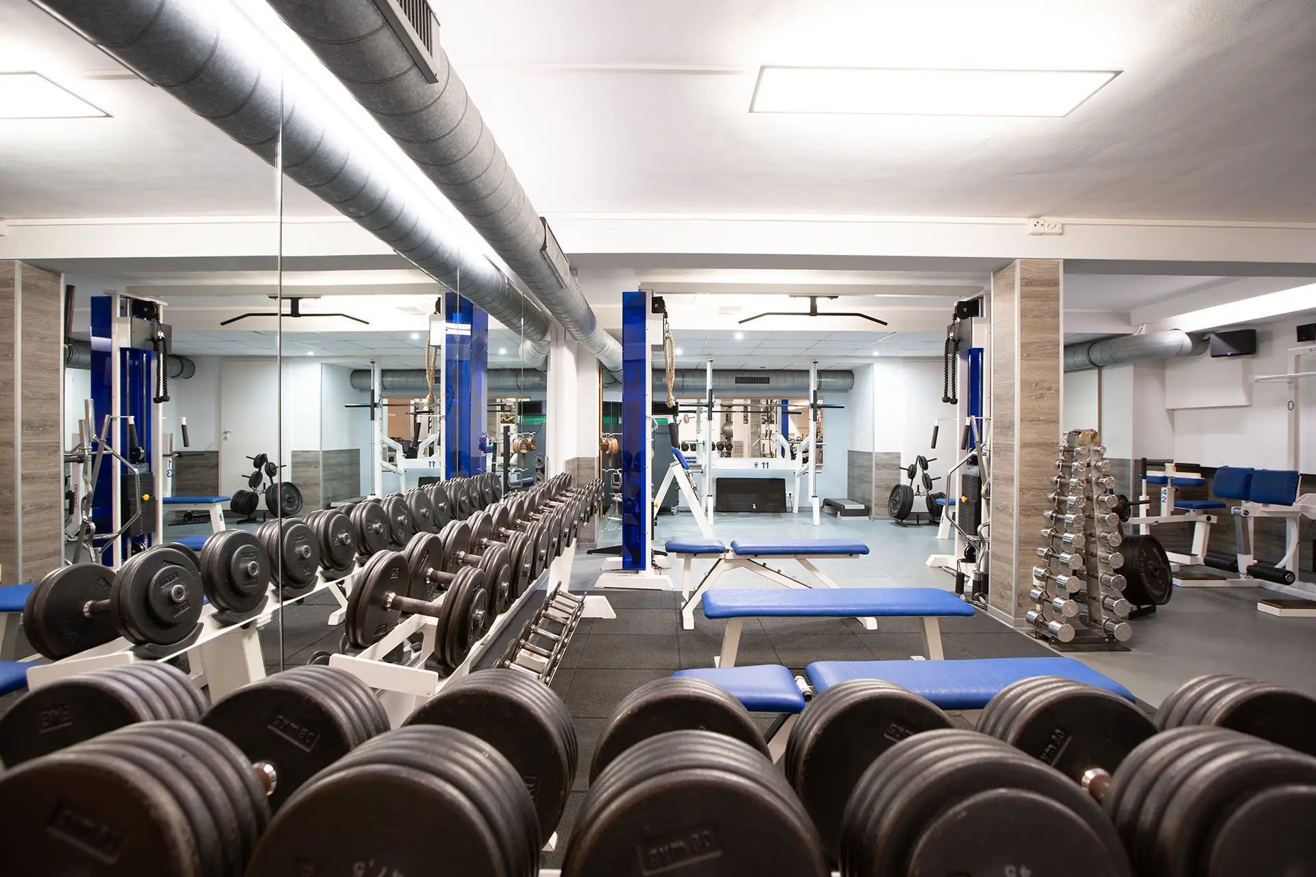 Krafttrainingsbereich mit Hantelbänken und Kurzhanteln im Fitnessstudio body & soul Billerbeck, Spiegelwand und Trainingsgeräte im Hintergrund