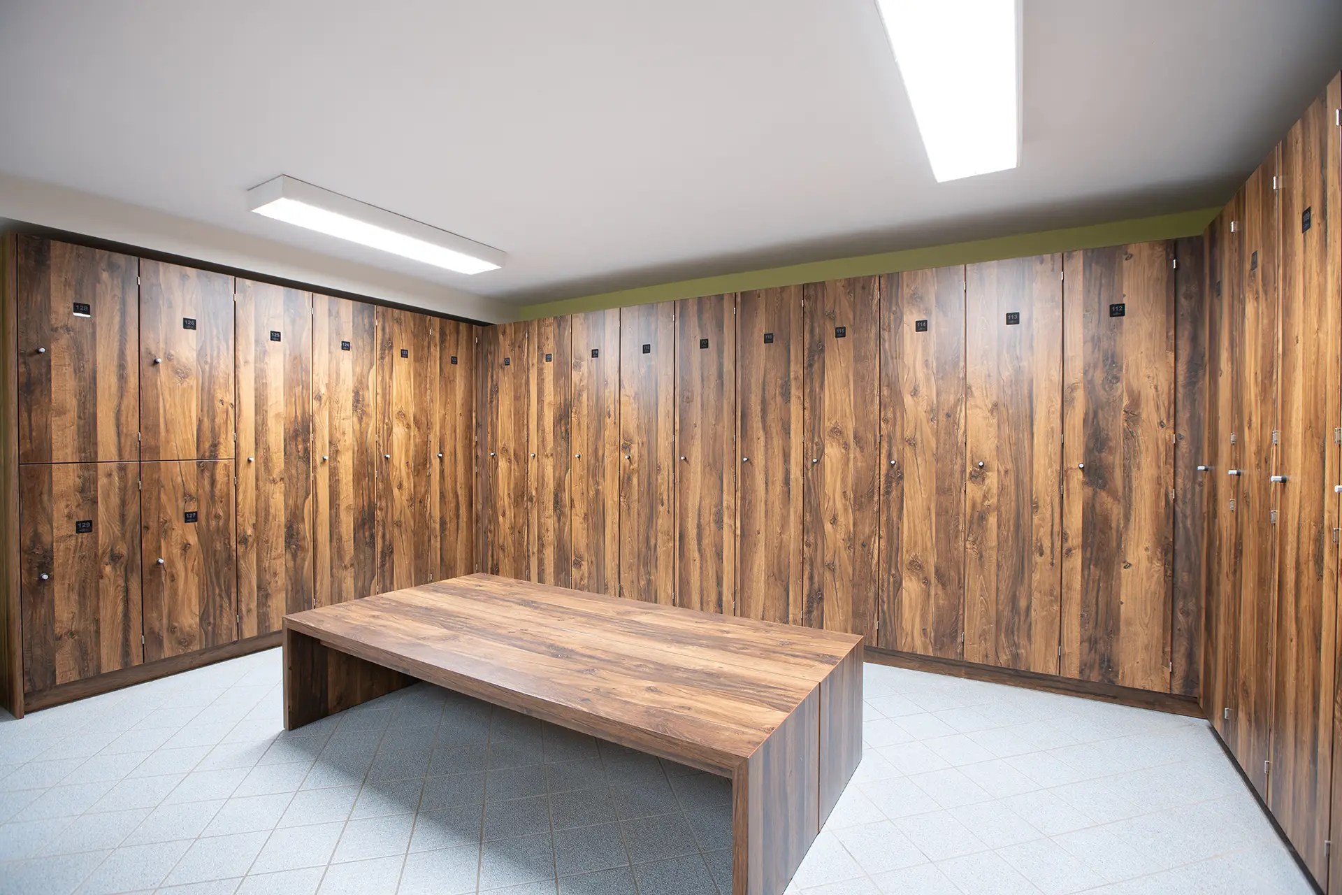 Heller Umkleideraum mit Holzspinden, Sitzbank und gefliestem Boden im Fitnessstudio Body & Soul in Billerbeck.