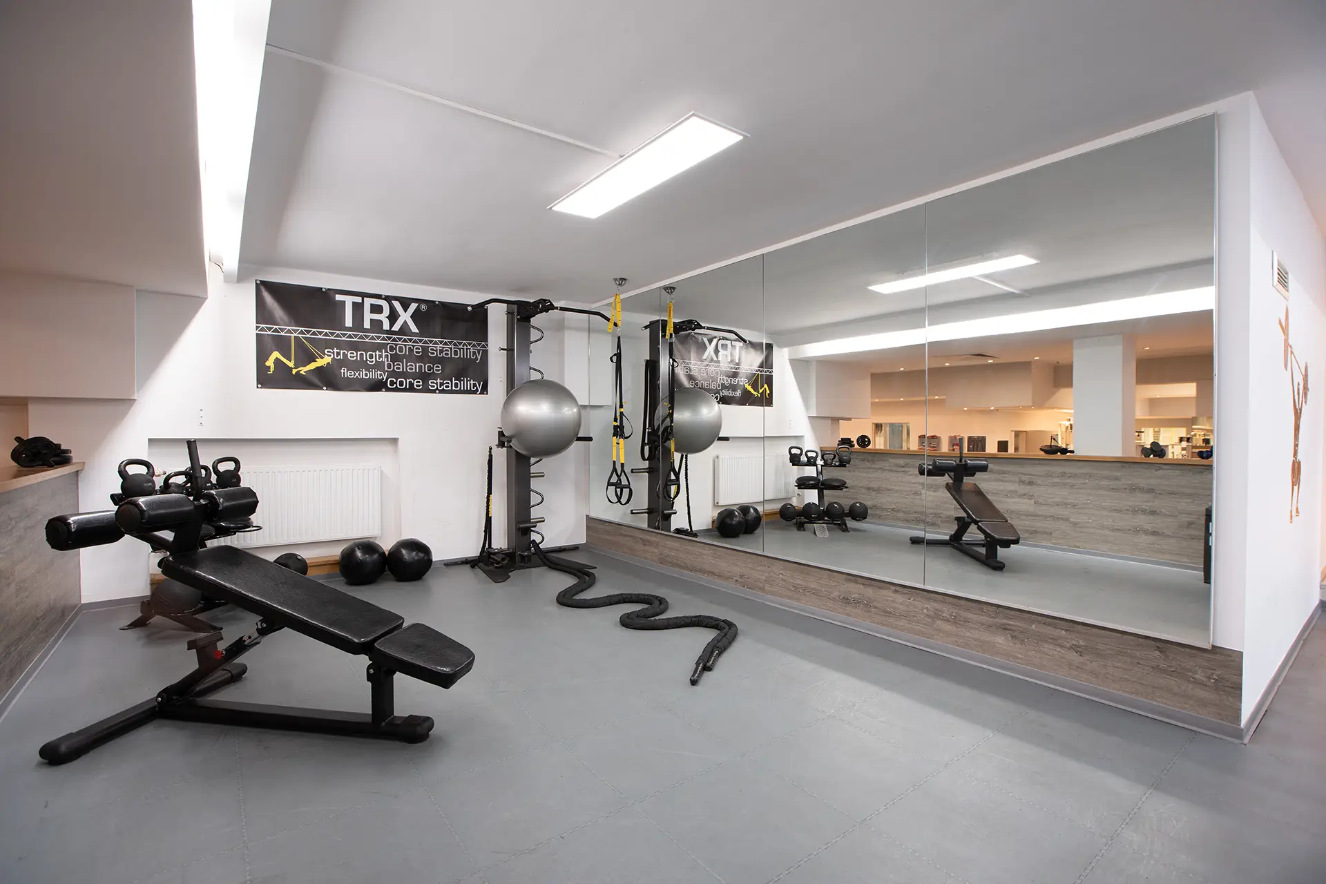 Blick in den TRX- und Functional-Trainingsbereich mit Hanteln, Trainingsbank, Sling-Trainern, Spiegelwand und Trainingsgeräten im Fitnessstudio Body & Soul in Billerbeck.