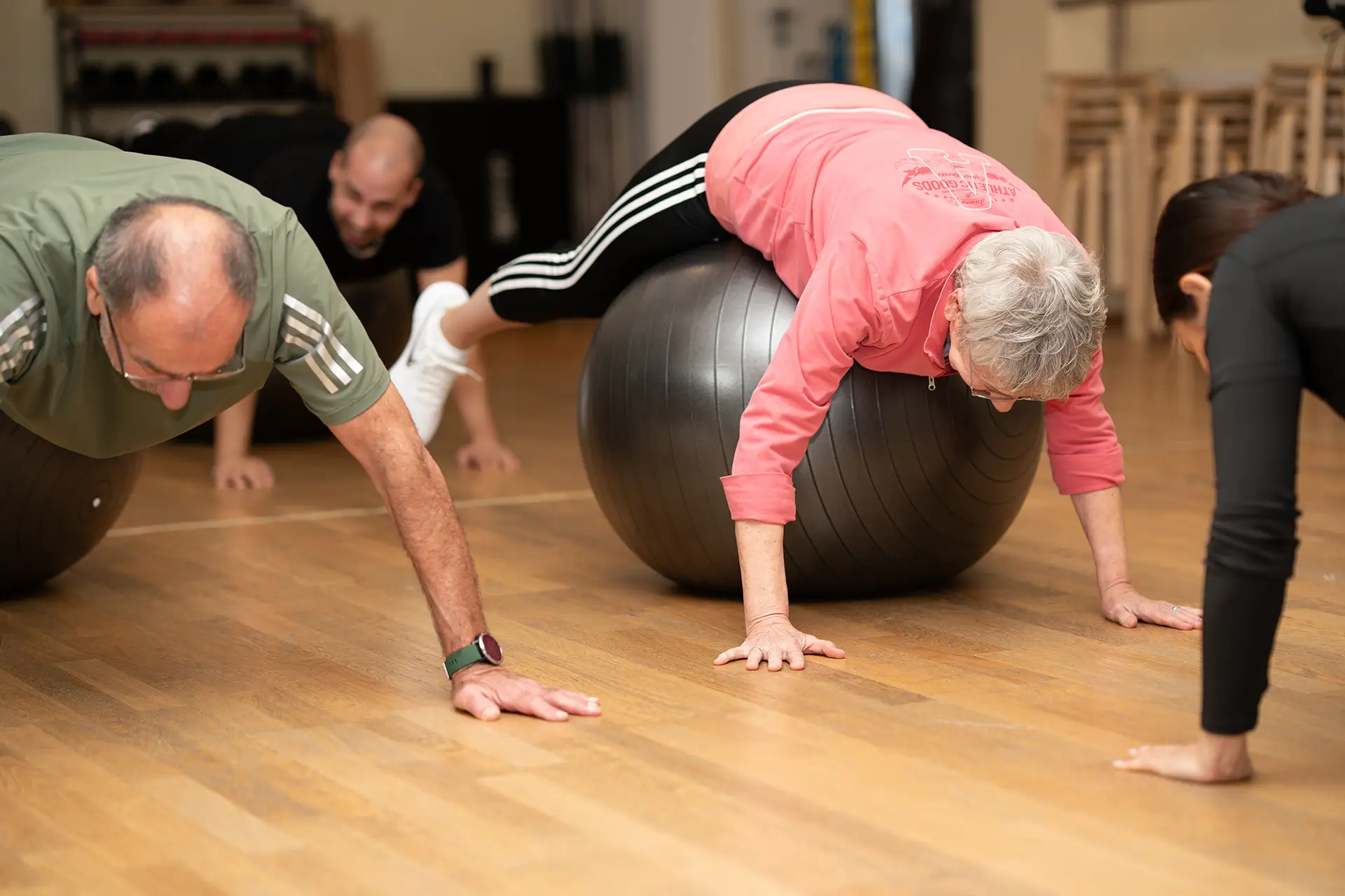 Gruppe führt Stabilisations- und Reha-Übungen mit Gymnastikbällen auf dem Boden im Fitnessstudio body & soul Billerbeck aus