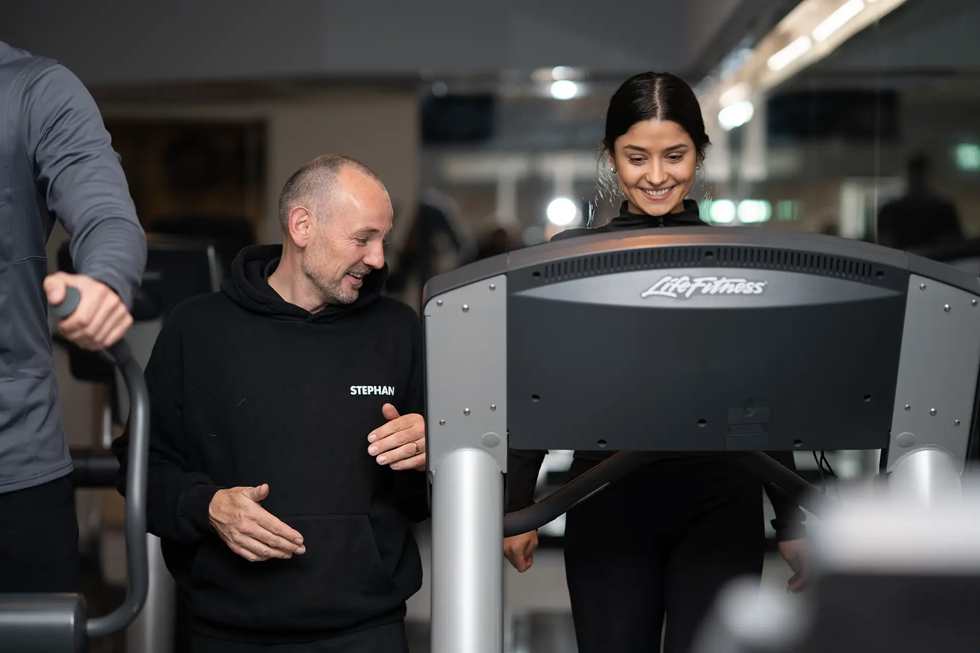 Trainer begleitet eine Frau beim Laufbandtraining im Fitnessstudio body & soul Billerbeck und erklärt die Einstellung des Geräts
