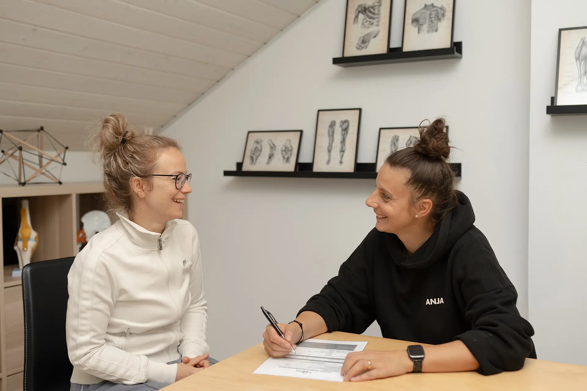 Trainerin führt ein persönliches Beratungsgespräch mit einem Mitglied am Tisch im Fitnessstudio Body & Soul in Billerbeck und füllt gemeinsam mit ihr einen Trainings- oder Anamnesebogen aus.